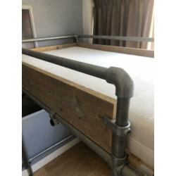 Stoere steigerhouten hoogslaper met steigerbuizen onderstel.