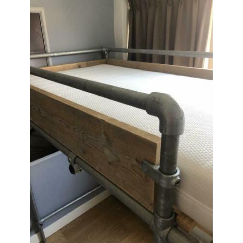 Stoere steigerhouten hoogslaper met steigerbuizen onderstel.