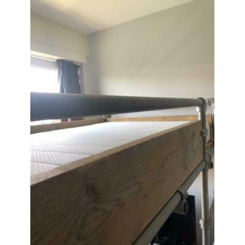 Stoere steigerhouten hoogslaper met steigerbuizen onderstel.